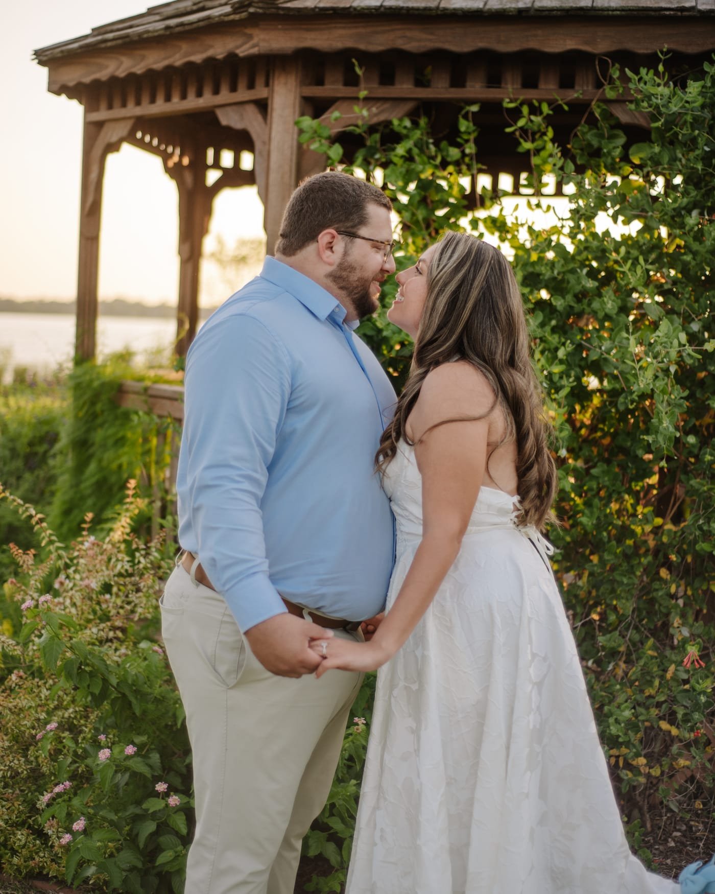 The two of them leaning in to kiss beside the gazebo, the water behind them.
